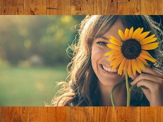 A woman looking at the camera, hiding one eye behind a sunflower.