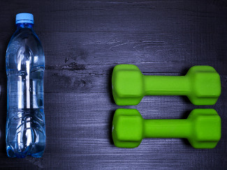 A photo of water and dumbbells representing to metabolism boosters: hydration and exercise.